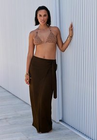 Top de bikini à motifs marron et jupe portefeuille marron unie. L'ensemble présente une fermeture à nouer simple et est complété par des accessoires métalliques.