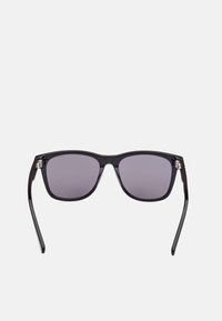 Gafas de sol negras en forma rectangular con lentes oscuros y montura de plástico brillante. Detalles metálicos en las bisagras. Sin patrones visibles.
