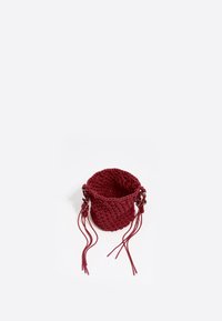 Cesta de mimbre roja con parte superior abierta, con asas trenzadas y borlas. Hecha de material texturizado, de forma redondeada y con base sólida.