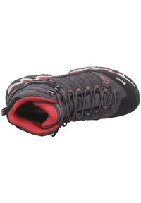 Chaussure de randonnée noire avec des accents rouges et gris, dotée d'un dessus texturé, de panneaux en maille et d'une semelle extérieure en caoutchouc robuste. Système de laçage visible.