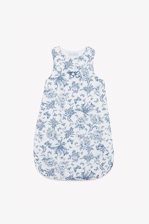 Floral-patterned cotton sleep sack in blue and white, sleeveless, rounded bottom, with embroidered accents near the neckline.