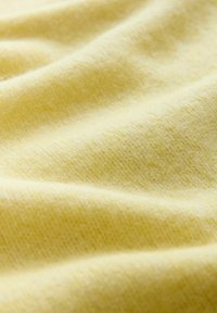 Blød, struktureret stof i en lys gul farve med en glat, let fuzzy overflade og subtile variationer i nuancen.