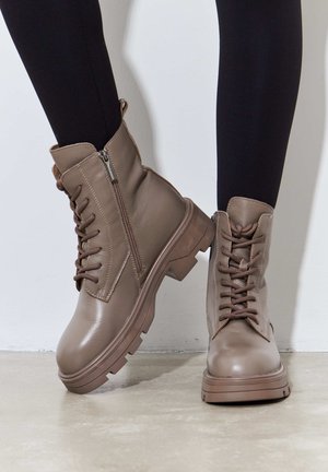 Brown leather ankle boots with a thick sole, featuring lace-up design and side zipper. Smooth texture with subtle stitching details.