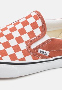 Schlüpf-Sneaker mit einem rot-weißen karomuster aus Canvas, schwarzem Gummisohle und einem kleinen Vans-Tag an der Seite.