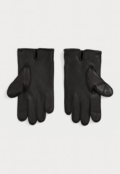 Une paire de gants en cuir noir avec des pouces coupés et une petite entaille au niveau du poignet sur chaque gant, posée à plat sur un fond blanc.