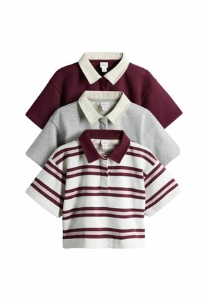 Trois polos à manches courtes empilés : rouge foncé uni, gris uni et blanc avec des rayures horizontales rouge foncé, chacun avec un col clair contrastant.