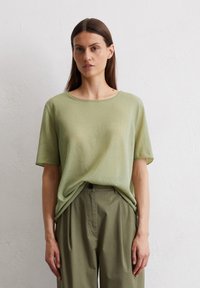 Light green short-sleeve t-shirt made of soft fabric, featuring a rounded neckline and relaxed fit, paired with loose khaki pants.