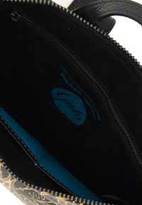 Interno di una borsa a mano in pelle nera con una fodera turchese, una tasca con zip e un'etichetta visibile che recita "Made in Italy."