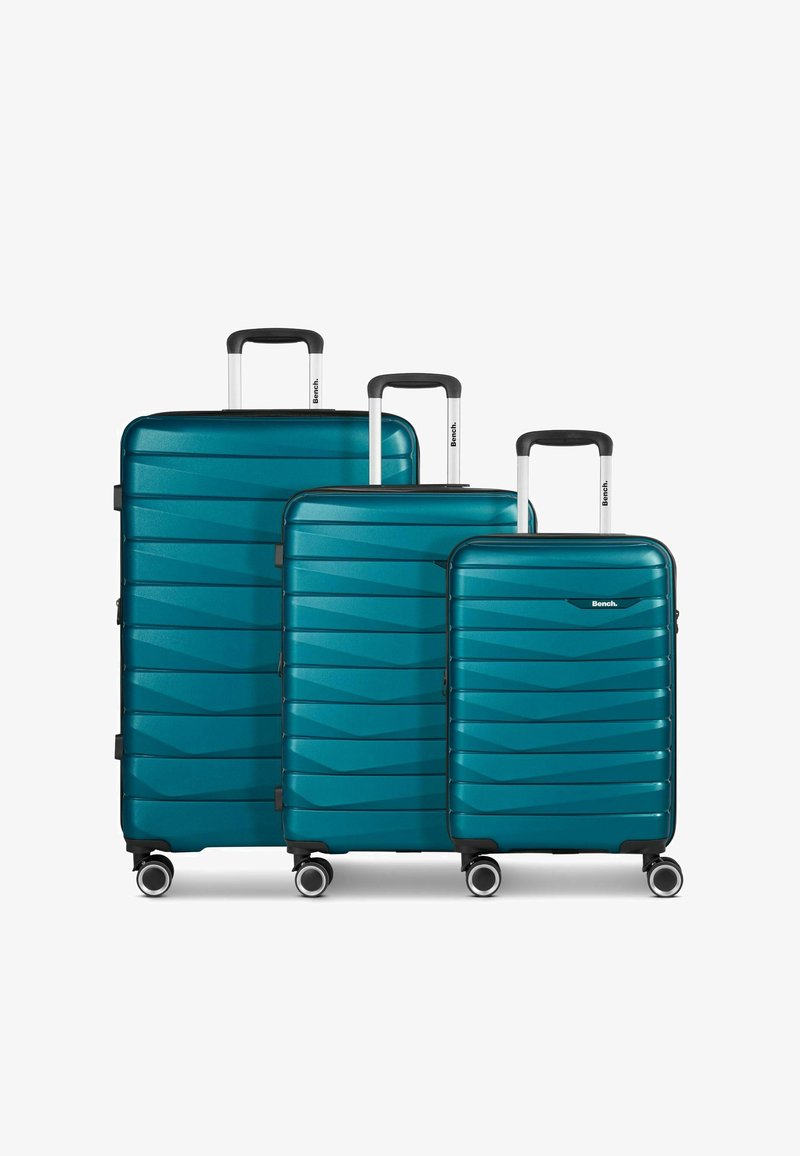 Drie harde koffers in teal, met een golfpatroon, een gladde textuur, uitschuifbare handvatten en vier draaibare wielen voor mobiliteit.