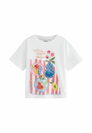 T-shirt bianco in cotone con maniche corte e scollo rotondo, decorato con una stampa colorata di fiori e frutti con paillettes su sfondo a righe.