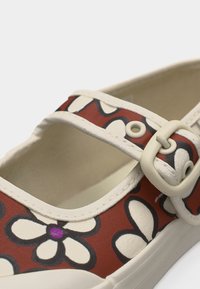 Παπούτσι στυλ Mary Jane με κόκκινο καμβά, μεγάλο λευκό λουλούδι, λευκή επένδυση και ρυθμιζόμενο λουράκι με αγκράφα.