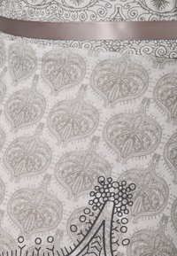 Tela ligera con un detallado patrón de hojas grises. Una amplia y suave cinta topo acentúa la cintura. Intricado diseño gráfico negro en la parte inferior.