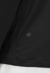 Top sport negru dintr-un material moale și neted, având un logo mic în colțul din jos și un design simplu, fără embellishments.