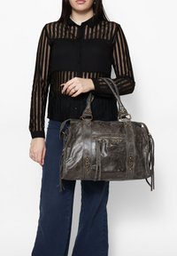 Borsa a tracolla in pelle grigia con finitura testurizzata, manici superiori, accessori decorativi e una tasca anteriore con zip. Include lunghi dettagli a frange.