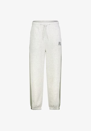 Lichtgrijze joggingbroek met elastische boorden, een tailleband met trekkoord, strepen aan de zijkant en kleine zwarte "SBVL STUDIO" tekst op de bovenste linker dij.