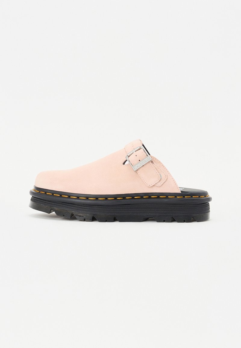 Chaussure en daim rose clair à enfiler avec une semelle épaisse noire, des coutures jaunes et une boucle argentée sur le côté supérieur.