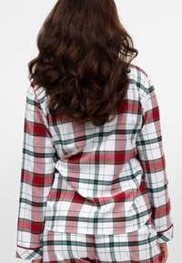Pajama set z długim rękawem w kratę w czerwono-zielono-białym wzorze, wykonany z miękkiego materiału, w luźnym kroju i prostym wykończeniu.