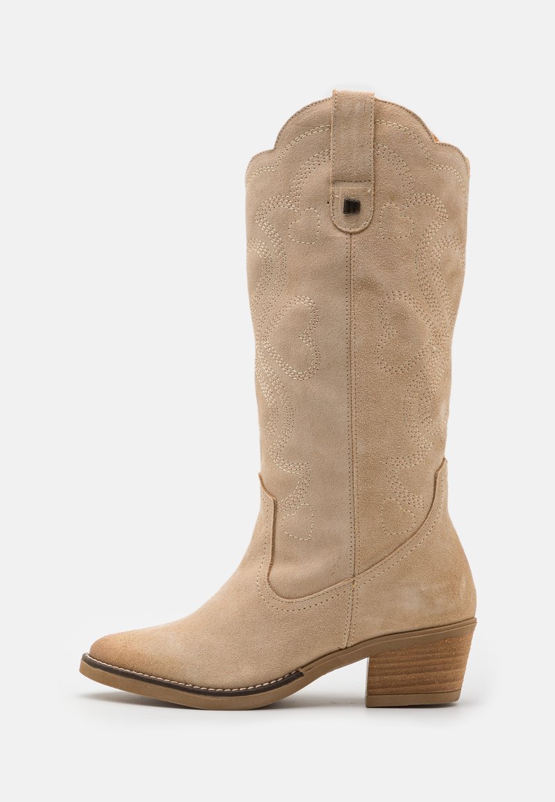 Beige Wildlederstiefel im Western-Stil mit spitzer Zehenform, dekorativen Nähten und einer geschwungenen Kragenkante. Abgeschlossen mit einem gestapelten Absatz.
