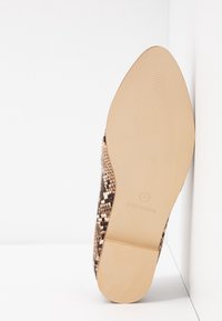 Ballerine à bout pointu en matériau synthétique avec un motif serpent dans des nuances de beige et de marron. Semelle plate en caoutchouc texturé.