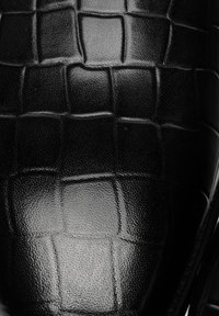 Černá kožená bota s texturovaným krokodýlím vzorem, hladkým povrchem a zaobleným tvarem. Výrazný lesk design zvýrazňuje.