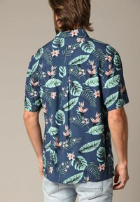Korte mouwen shirt in marineblauwe stof met een levendig tropisch blad- en bloemenpatroon in tinten groen en roze.