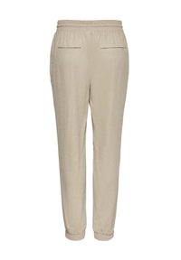 Beige jogger pants met een elastische tailleband, twee achterzakken en ribbelmanchetten. Zachte textuur en taps toelopend ontwerp.