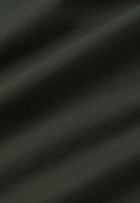 Donkergroene stof met een ribbeltextuur, die een gladde, zachte oppervlakte en een subtiele glans vertoont. De vezels zijn stevig geweven voor duurzaamheid.