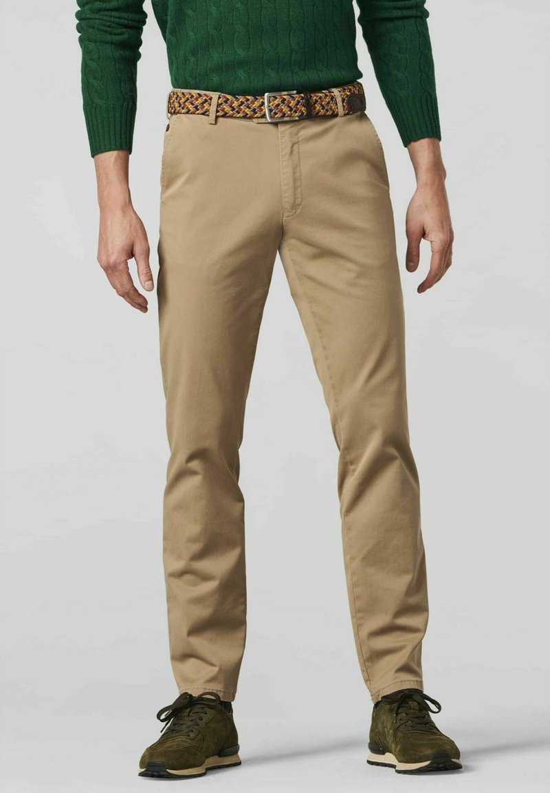 Beige chinos with a slim fit, featuring front pockets and a woven multicolored belt. Paired with dark green textured sweater and black sneakers.