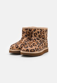 Leopard-print ankle boots made of suede with a cream lining, tan rubber sole, and stitched accents along the seams.