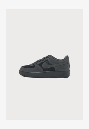 Adidași negri Nike Air Force 1 low-top cu partea superioară din plasă și piele, închidere cu șiret și talpă de cauciuc pe fundal simplu.