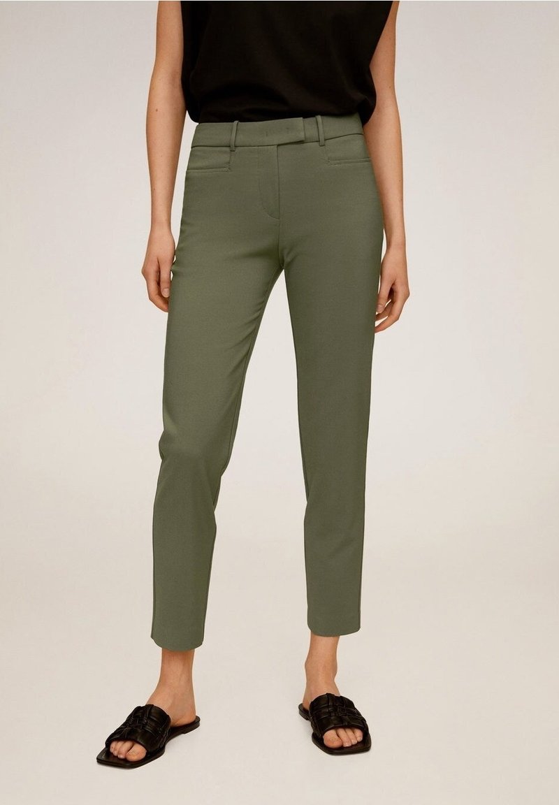 Pantalons ajustés vert olive avec une coupe slim, dotés de poches avant et d'une texture lisse, associés à des sandales noires à enfiler.