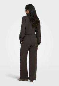 Brun, oversized sweatshirt og brede bukser i et blødt, struktureret stof. Designet har en afslappet pasform med en elastisk talje.