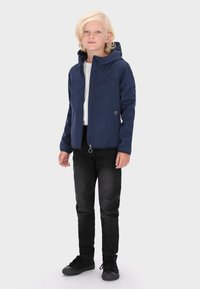 Marineblau Jacke mit Kapuze, Reißverschluss, Seitentaschen und subtilen Nähten, kombiniert mit schwarzen Jeans und schwarzen Sneakers.