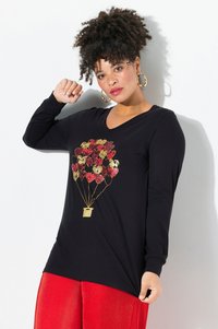 Schwarz langärmliges Shirt mit einem goldenen und roten Grafik von einem Heißluftballon. Kombiniert mit strukturierten roten Hosen, die ein lässiges Design betonen.