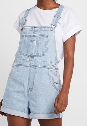 Lichtblauwe denim overall met verstelbare banden, voorzak en drukknoopjes aan de zijkant. Opgerolde hemden op de shorts voor een casual, losse fit.