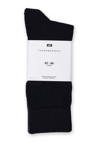 Schwarze Baumwollsocken in einem Drei-Pack angeordnet, mit einem weißen Etikett, das die Größe 43-46 und den Produktnamen "FUNDAMENTALS" angibt. Glatte Textur.