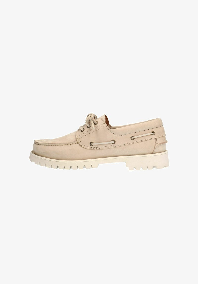 Beige suède schoen met een ronde neus, eenvoudig vetersluiting ontwerp en witte rubberen zool met diepe groeven voor grip.