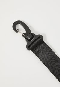 Black nylon strap with a textured surface, featuring a sturdy plastic clip for attachment. The strap is flat and has reinforced stitching.