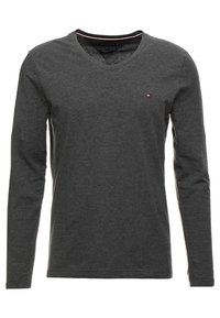 Dunkelgraues Langarmshirt mit V-Ausschnitt und kleinem rot-weiß-blauen Logo auf der linken Brust, aus weichem Stoff.