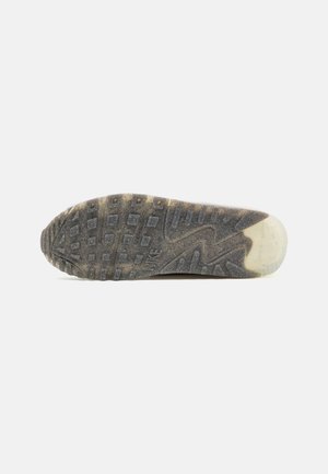 Sole of a worn black and gray Nike sneaker with textured tread pattern and translucent heel section on a white background.