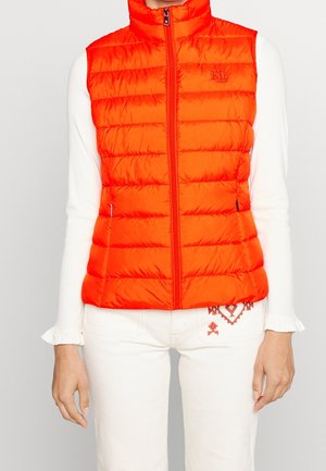 Orangene gepolsterte Weste mit hohem Kragen, Reißverschluss, Logo-Akzent und gestepptem Design, getragen über einem weißen Langarmshirt und hellen Hosen.
