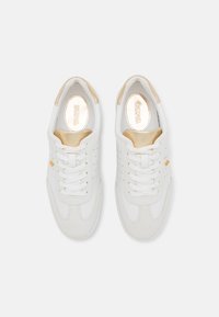 Witte sneaker van glad leer met suède accenten, voorzien van perforaties en platte veters. Gouden logo aan de zijkant, gewatteerde kraag en subtiele glans.