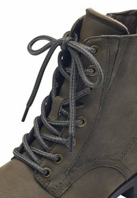 Botín de cuero color verde oliva con una textura suave, que presenta ojales metálicos, cordones trenzados y un cuello acolchado.
