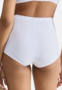 Białe majtki z wysokim stanem wykonane z miękkiej bawełny, charakteryzujące się gładką fakturą, falbankową elastyczną lamówką i pełnym pokryciem.