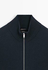 Pull en coton côtelé bleu marine avec col montant et zip argenté, étiquette Massimo Dutti, fabriqué en Chine.