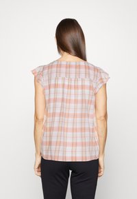 Blouse légère à carreaux dans des couleurs pastel douces avec manches courtes et détail froncé au dos. Offre une coupe décontractée et une texture lisse.