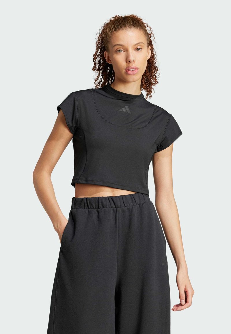 Svart kortärmad träningstopp med hög krage, tillverkad av slät tyg. Matchad med högmidjade svarta byxor med sidofickor.