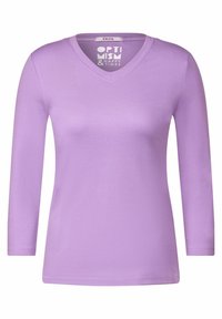 Długi rękaw lawendowa koszulka V-neck wykonana z miękkiego materiału o gładkiej fakturze i subtelnym połysku. Posiada metkę z brandingiem "Cecil".