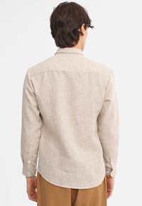 Camicia button-up beige chiaro con motivo testurizzato, maniche lunghe con polsini bottonati e orlo curvo. Realizzata in tessuto tessuto.