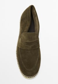 Olive green suede slip-on loafer with a padded front band and contrasting stitching; flat, textured sole with a rope-like detail around the edge.